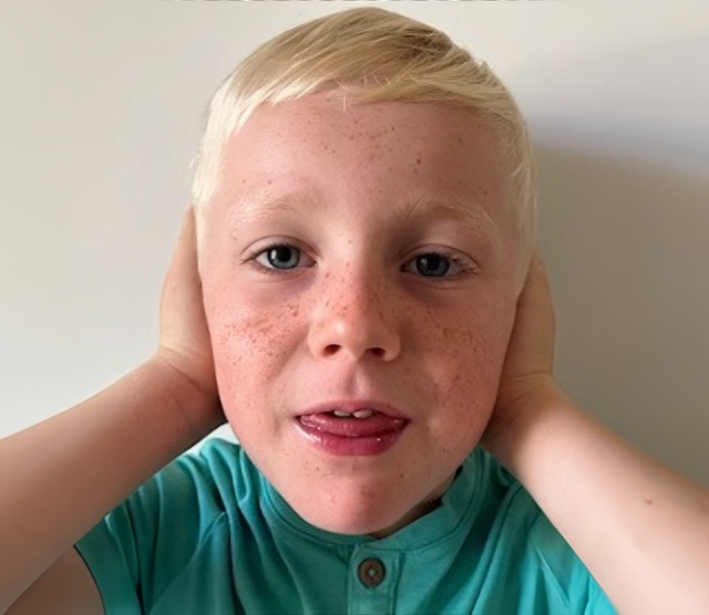 A boy with his hands over his ears