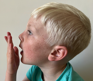 A boy with his hand over his mouth